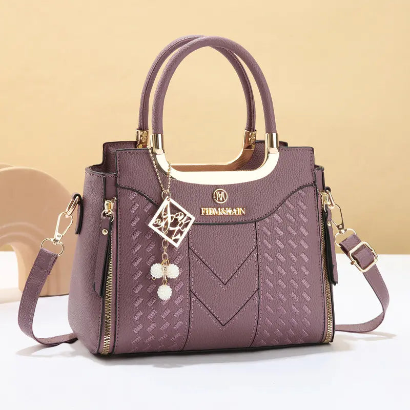 Bolso bandolera para mujer con costuras en forma de V, herrajes dorados, múltiples compartimentos y asa superior.